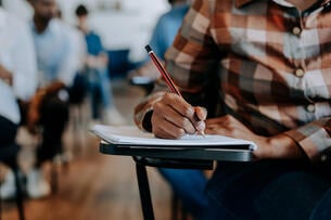 Adult writing in the classroom at a desk