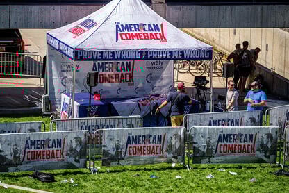 A scene of the Utah Valley University event after the shooting of Charlie Kirk on Sept. 10: a few people mill around the tent under which he had been speaking, which bears the words "American Comeback Tour: Prove Me Wrong." 