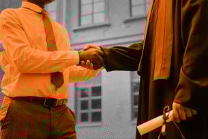 Close-up of a teacher shaking hands with student at graduation.