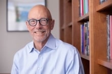 Ted Mitchell, a light-skinned man wearing glasses and a blue button-down shirt.